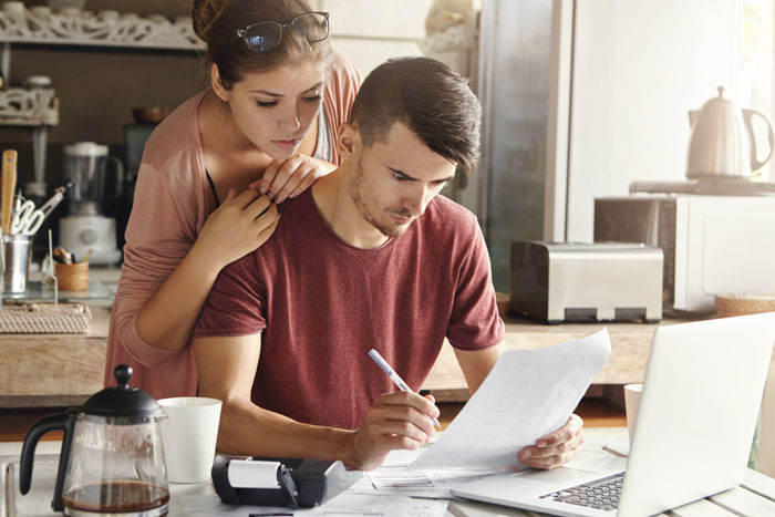 Couple at home reviewing documents together, illustrating a cheese wheel girlfriend relationship in a cozy kitchen setting.