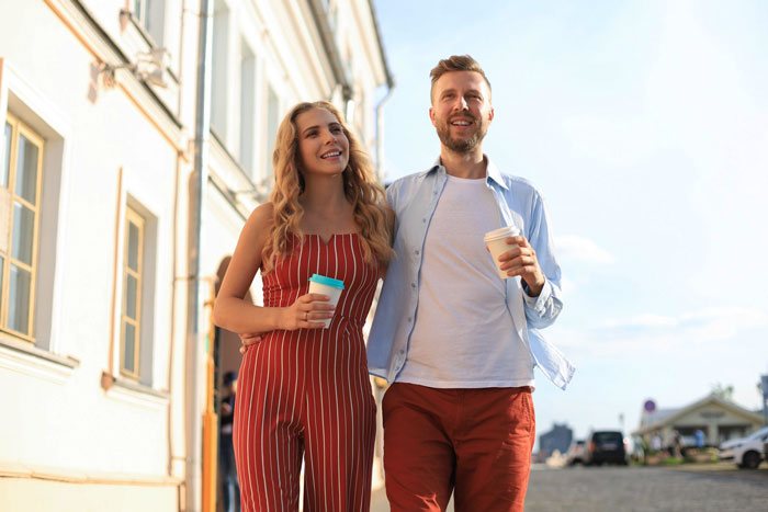 Young couple walking outdoors happily, holding coffees, illustrating concepts related to child out of spite behavior. Young couple walking outdoors happily, holding coffees, illustrating concepts related to child out of spite behavior.