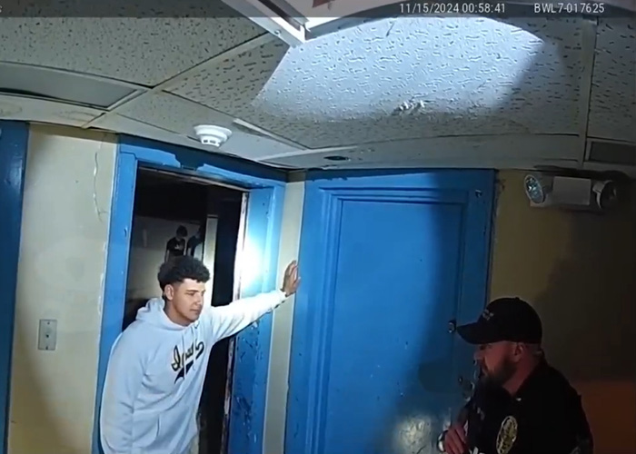 Police officer and young man in hallway during fraternity hazing event with an eerie atmosphere captured on video.