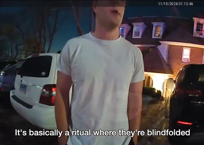 Young man in white shirt speaking outside a house during police interruption at fraternity hazing event captured on video.