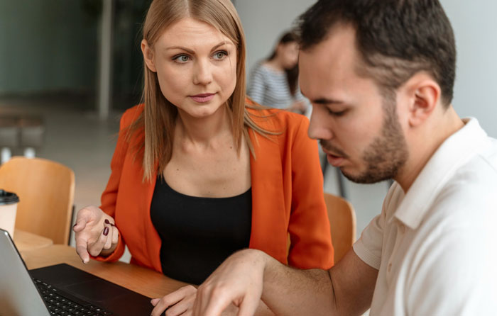 Coworker reporting concerns to HR in an office setting with serious expressions during a work discussion. Coworker reporting concerns to HR in an office setting with serious expressions during a work discussion.