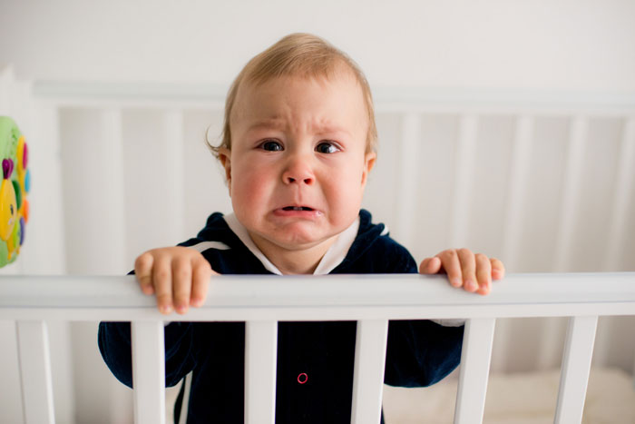 Crying baby in crib representing concerns leading to lady secretly reporting sister to CPS for responsibility.