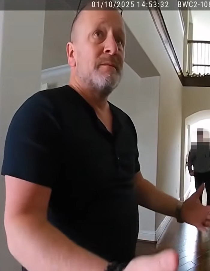 Man in black shirt inside home, captured by police body camera, related to legal expert explaining no charges in family case.
