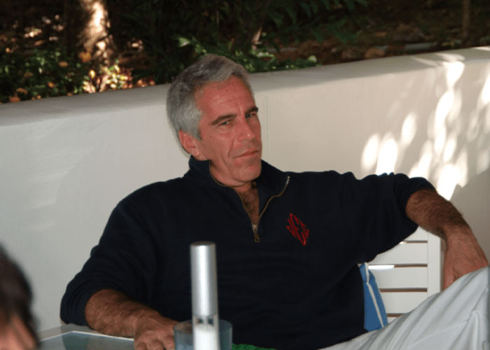 Man with gray hair in a black pullover sitting on a white chair outdoors, related to Dalai Lama Epstein files topic.