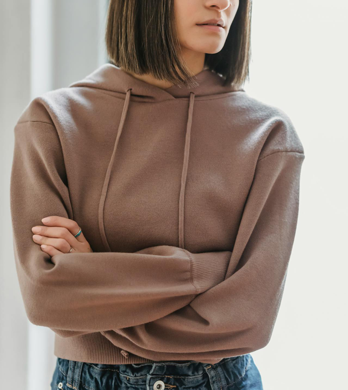 Woman wearing a brown hoodie with arms crossed, upset after learning people’s thoughts on her 20k wedding a year later