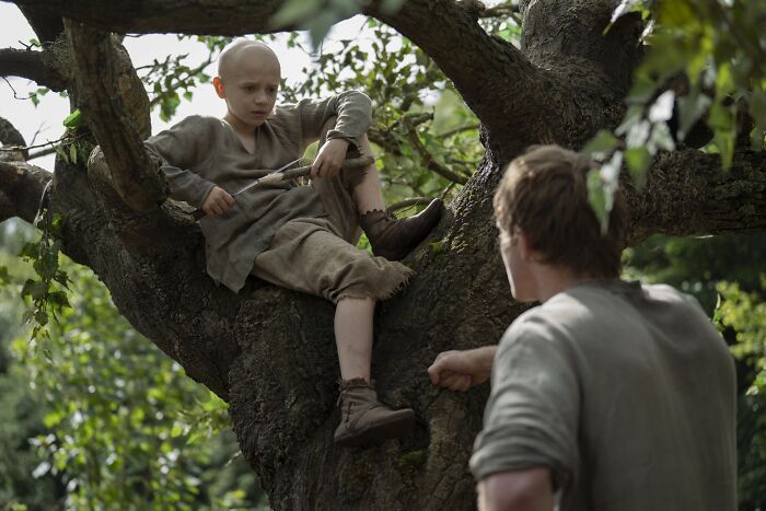 Young boy known as Egg sitting in a tree talking to a man, depicting a scene from Knight Of The Seven Kingdoms episode 3. - 1