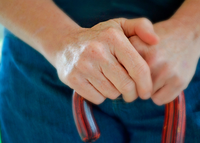 Close-up of hands gripping a wooden cane, illustrating doctors breaking down ignored signs of MS symptoms.