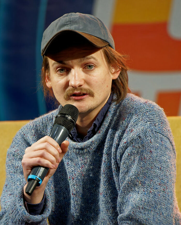 Young man with mustache and cap speaking into microphone, representing iconic actors who dominated Hollywood but vanished.