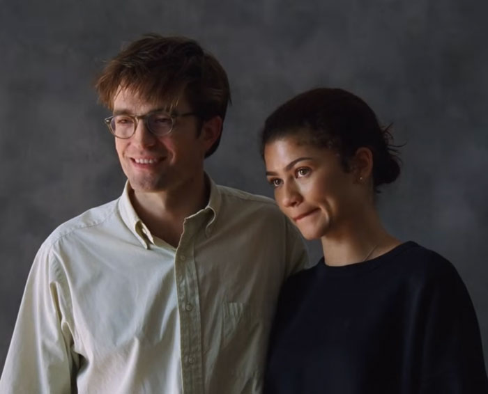 Zendaya and Robert Pattinson in a gender-bending photoshoot posing together against a dark, neutral background.