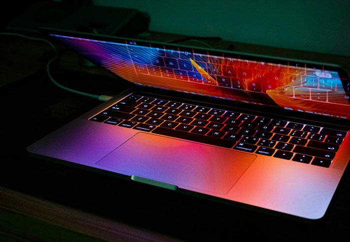 A laptop with colorful screen reflections on the keyboard, symbolizing criminals shockingly bad at technology skills.