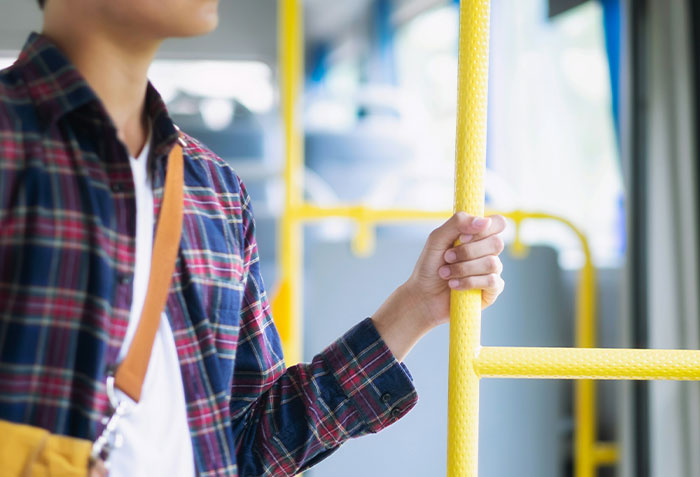 Person wearing a plaid shirt holding a yellow pole inside a bus, illustrating moments criminals were shockingly bad at what they do.