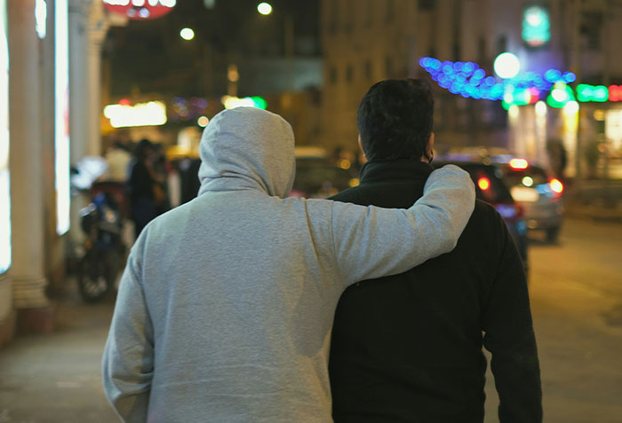 Two men walking on a city street at night, one with a hoodie, illustrating criminals shockingly bad at what they do.