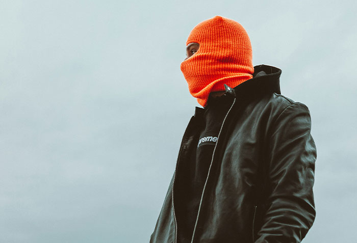 Person wearing an orange balaclava and black leather jacket, representing criminals who are shockingly bad at what they do.