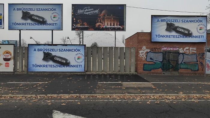 Billboards with political messages and graffiti on a gray, deserted street creating a dystopian nightmare atmosphere.