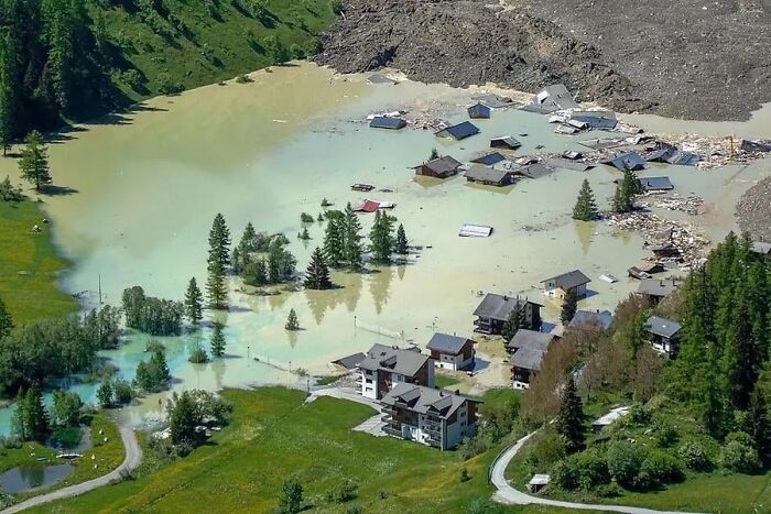 Flooded village with submerged houses and trees, creating a dystopian nightmare scene from around the world.