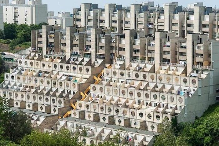 Concrete apartment complex with repetitive geometric patterns, resembling a dystopian nightmare cityscape.