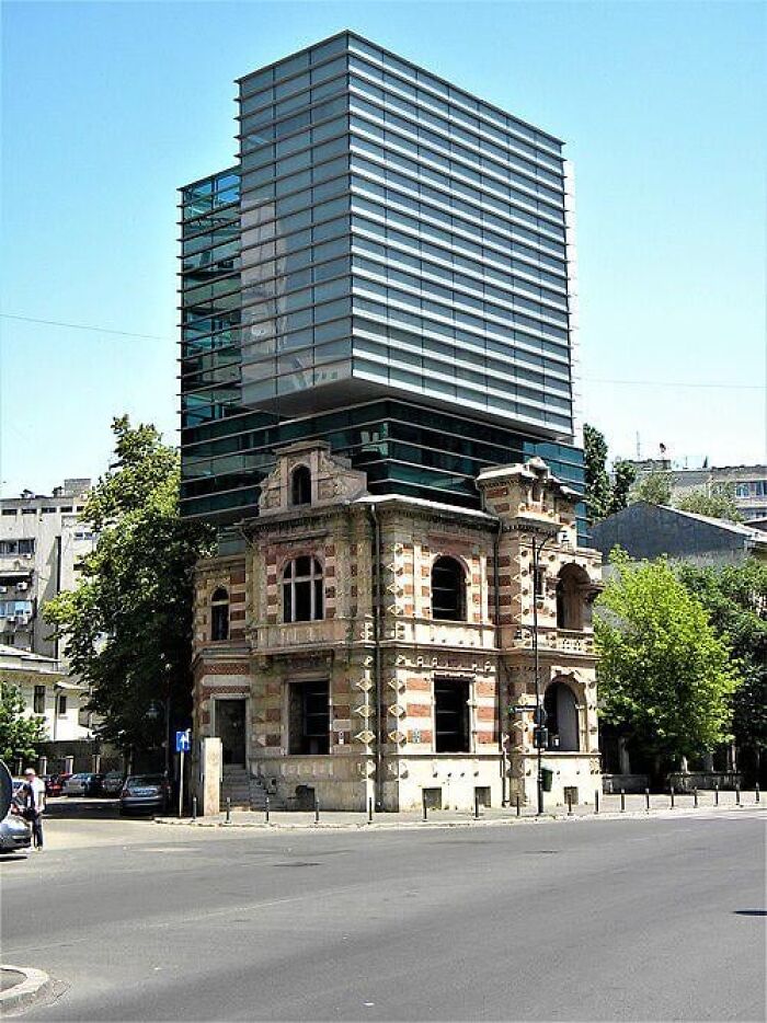 Old abandoned brick building with a modern glass structure attached, creating a dystopian nightmare appearance in an urban setting.