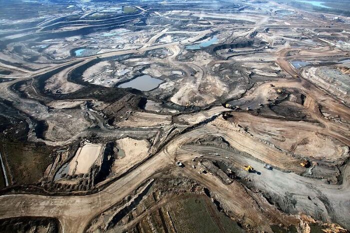 Aerial view of a barren, excavated landscape resembling a dystopian nightmare with twisted earth and scattered machinery.