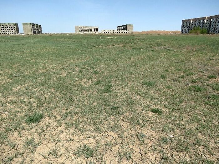 Abandoned buildings in a dry, c*****d field, creating a dystopian nightmare scene of desolation and decay.