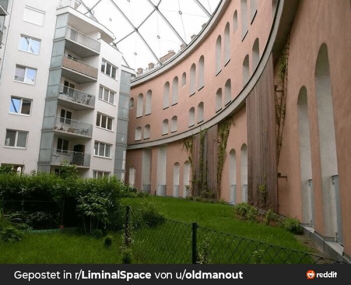 Curved building facade with boarded windows and green courtyard, evoking a dystopian nightmare atmosphere.