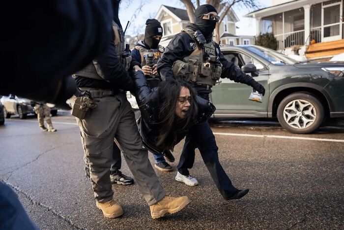 Police officers detaining a distressed woman on a city street, evoking a dystopian nightmare scene.