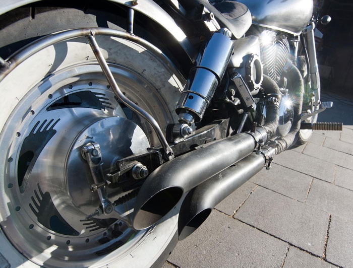 Close-up of motorcycle exhaust and rear wheel showcasing bike spare parts involved in profit from selling a bike purchase.