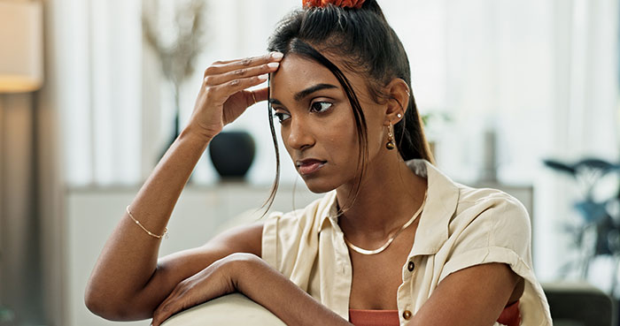 Woman looking stressed and contemplative indoors, reflecting the tension about rearranging schedule for nephew and respect issues. Woman looking stressed and contemplative indoors, reflecting the tension about rearranging schedule for nephew and respect issues.