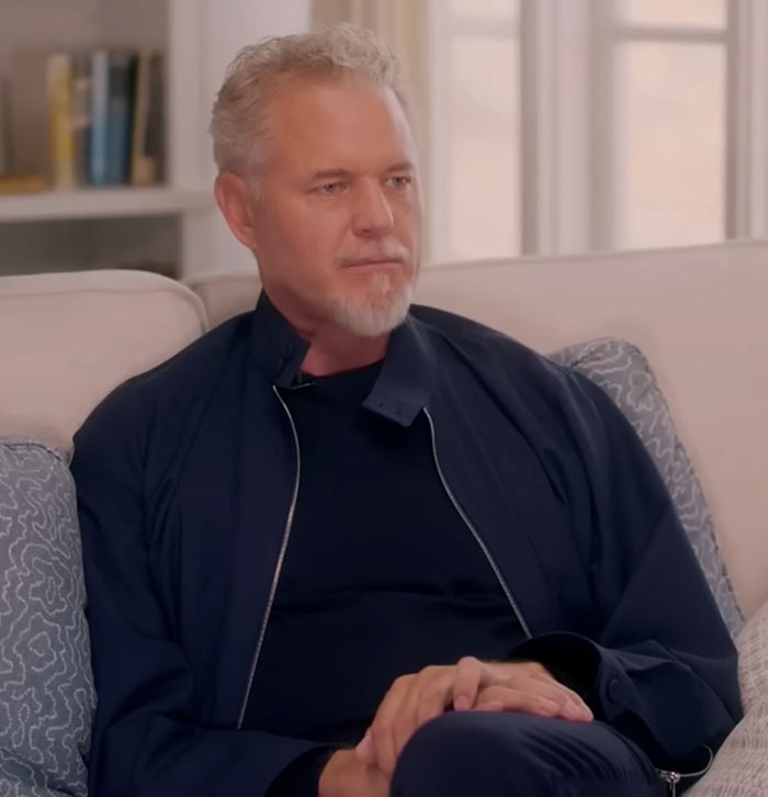 Man in casual dark clothing sitting on a couch in a well-lit room discussing commonly ignored ALS symptoms.