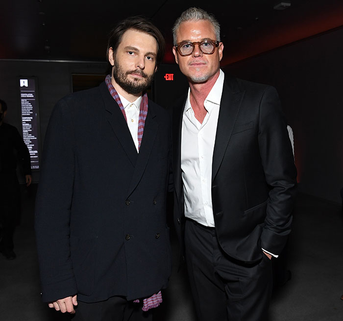 Two men in dark suits posing indoors, highlighting Eric Dane’s stunning first symptom that led to ALS diagnosis.