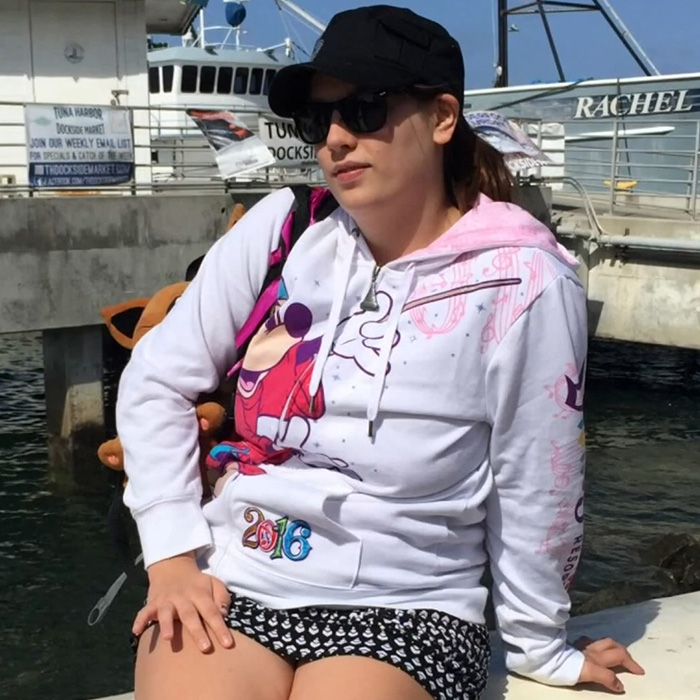 Young parent wearing sunglasses and a cap sitting near a dock, related to horrifying exchange after baby girl’s passing.