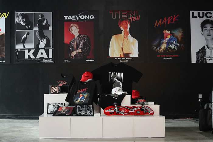 K-Pop fan displays rare merch including posters, shirts, and hats while alleged real owner demands item return online.