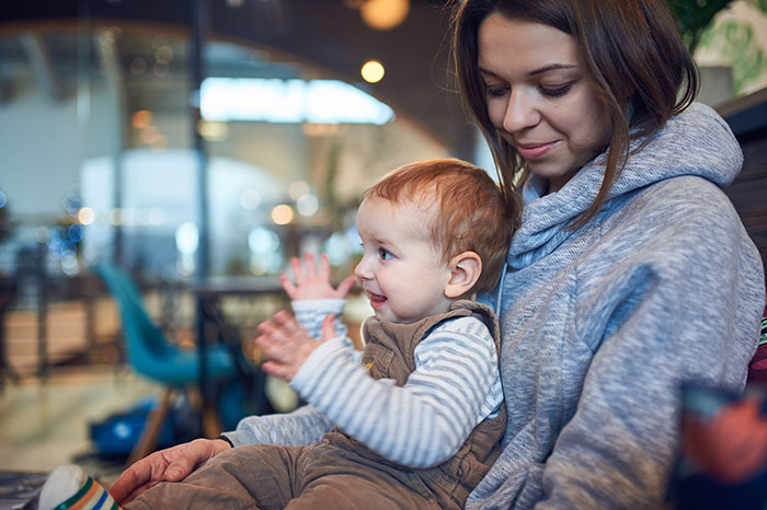 Mother holding baby boy during casual family dinner in cozy setting, capturing warm family dinner moment without rude behavior.