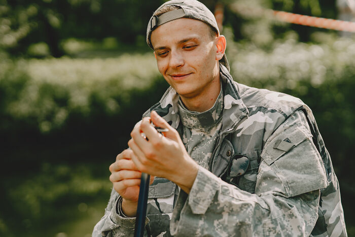 Young man in military uniform and cap outdoors, reflecting on the emotional reality of being related to an ICE agent