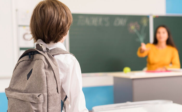 Young student with backpack facing teacher in classroom, illustrating emotional reality of being related to an ICE agent.