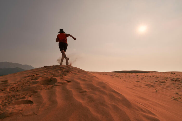Person running on desert sand dunes under a sunlit sky, symbolizing emotional reality related to ICE agent family.