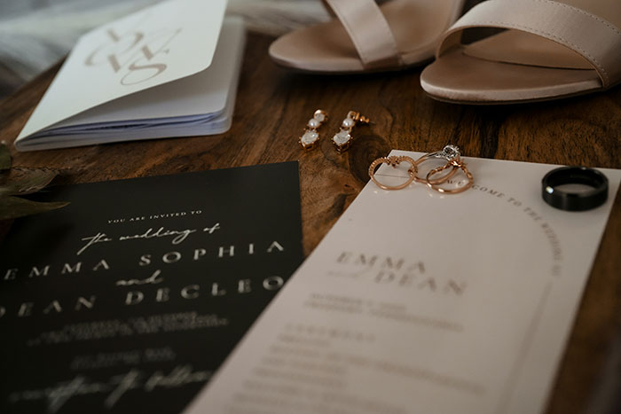 Wedding invitation and rings on a table, symbolizing marriages and family patriarch issues in estranged siblings&rsquo; story.
