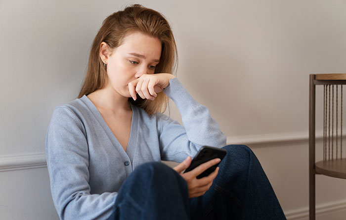 Young woman looking distressed while holding a phone, reflecting on family patriarch and brothers' collapsing marriages.