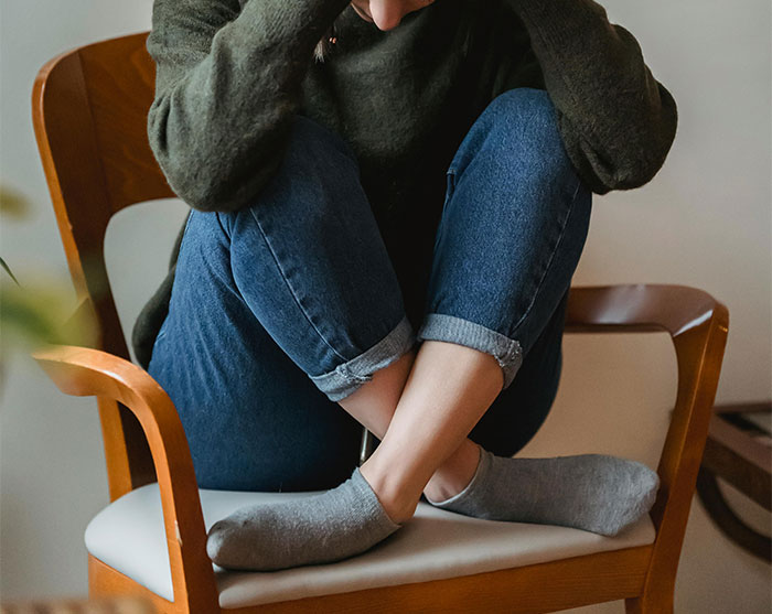Woman sitting curled up on a chair, looking distressed after learning about fianc&eacute;&rsquo;s family tradition ending wedding plans.