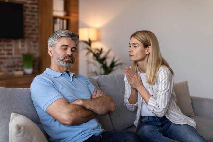 Dad's girlfriend excited about pregnancy while daughter looks horrified during a tense conversation at home on the couch.