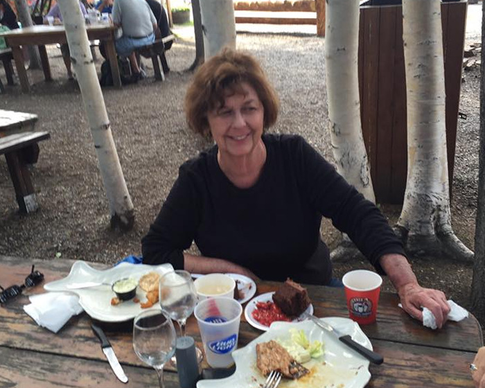 Older woman sitting at a picnic table with food and drinks outdoors, related to FBI details on ransom note case.