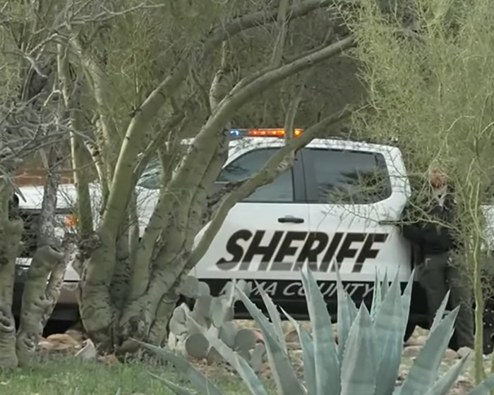 Sheriff vehicle parked near trees as forensics set up a white tent at a home days after a kidnapping investigation.