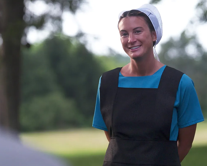 Young woman in Amish clothing smiling outdoors, representing former adult star joining Amish community in Pennsylvania.