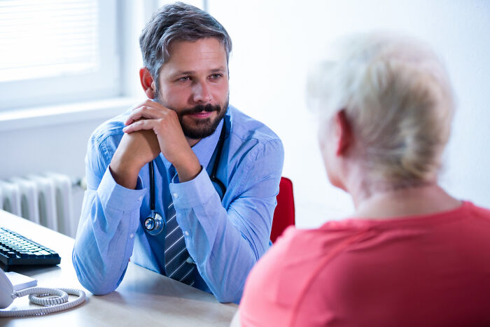 Male physician attentively listening to female patient during consultation in a bright medical office discussing physicians notes.