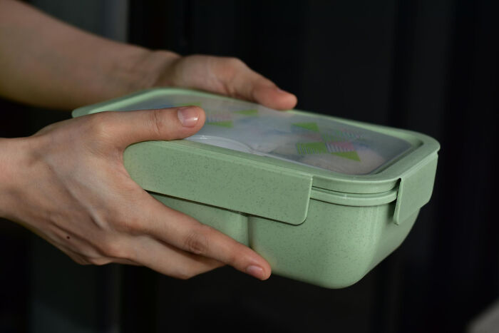 Person holding a green lunchbox representing a daily dose of laughter through hilarious physicians notes concept.