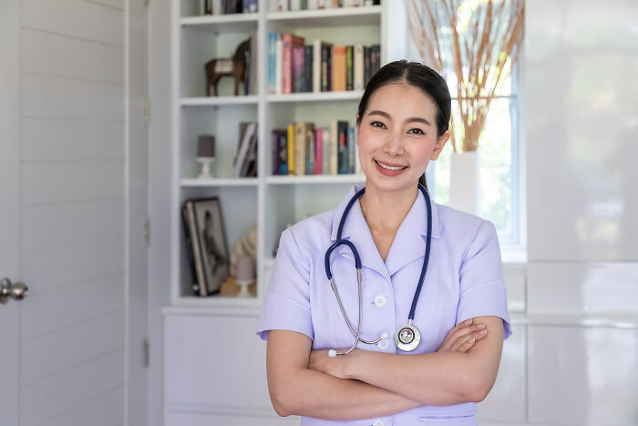Female nurse with stethoscope smiling confidently in a medical office, representing anesthesia and patient care.