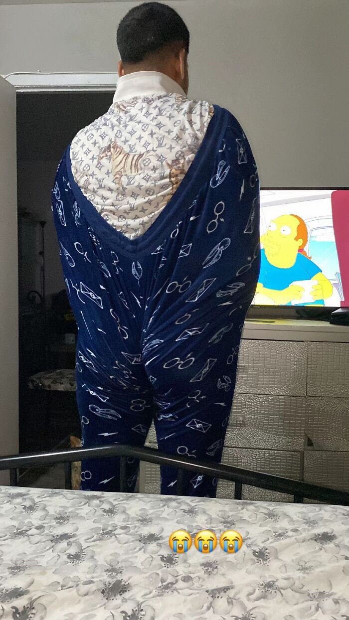 Man awkwardly wrapped awkward body language standing in pajamas watching TV in a bedroom setting.