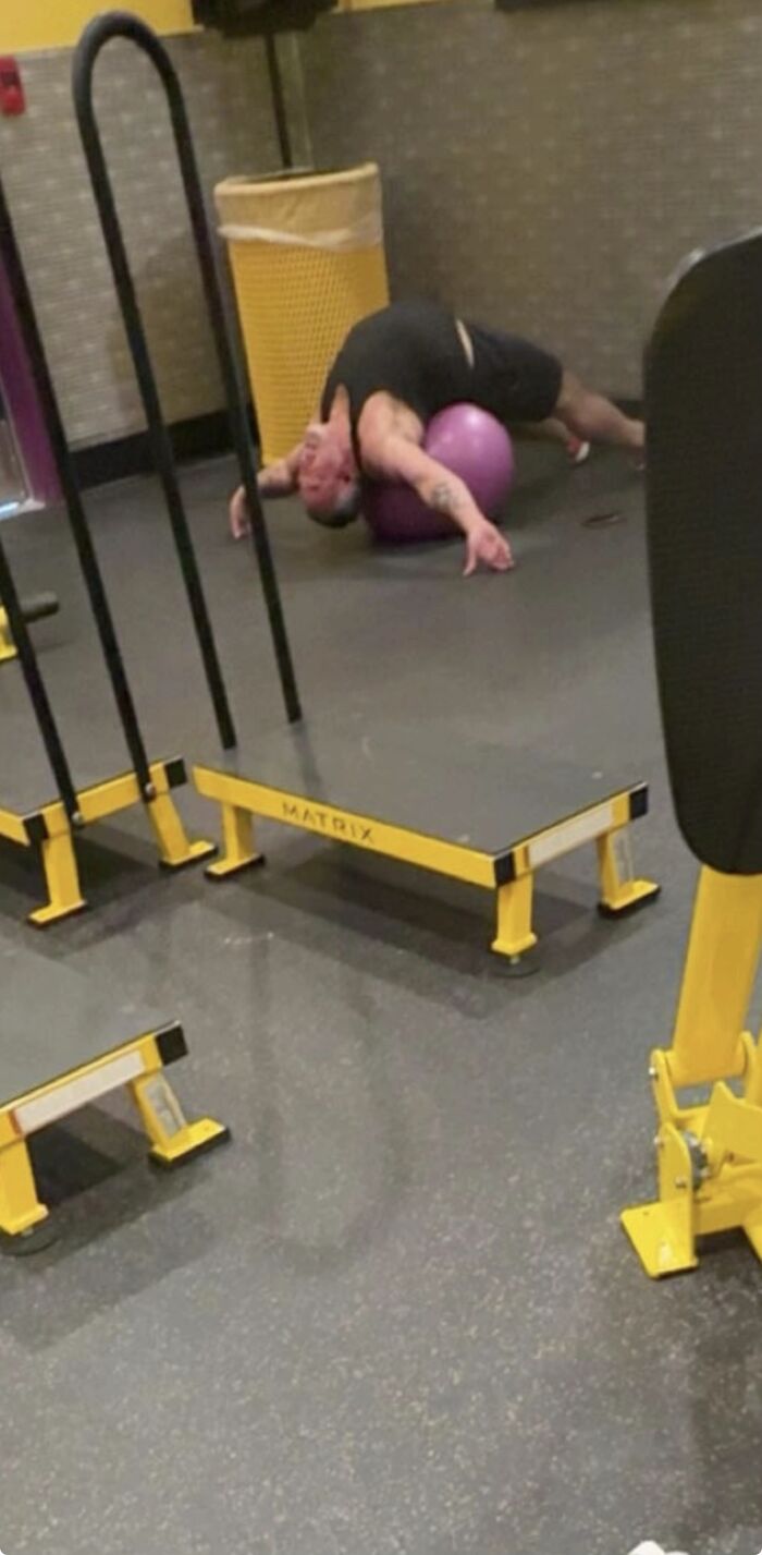 Man displaying hilariously awkward body language while stretching over an exercise ball in a gym setting.