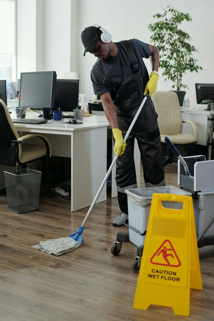 Man mopping office floor with caution wet floor sign, symbolizing stories of friendships ended without starting.
