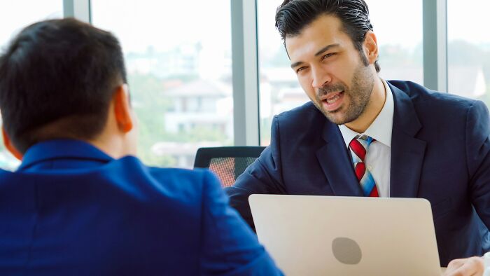 Two men in suits having a serious conversation indoors, illustrating shocking stories of how friendships ended early.