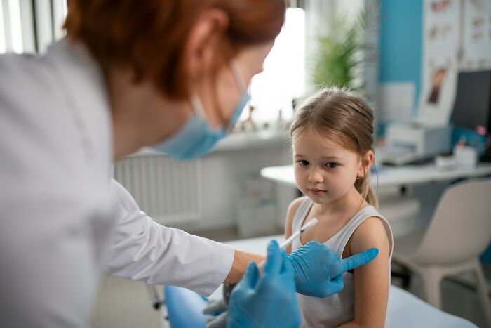 Doctor wearing gloves and a mask preparing to vaccinate a young girl in a medical office, illustrating unexpected friendship endings.